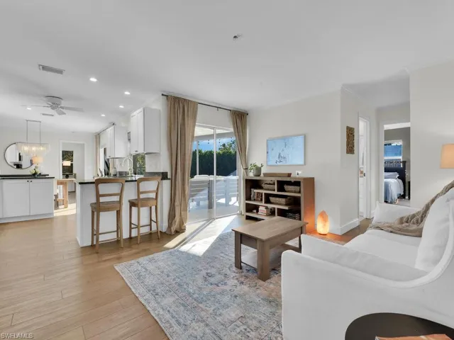 Living room featuring ceiling fan, light wood-type flooring, and ornamental molding
