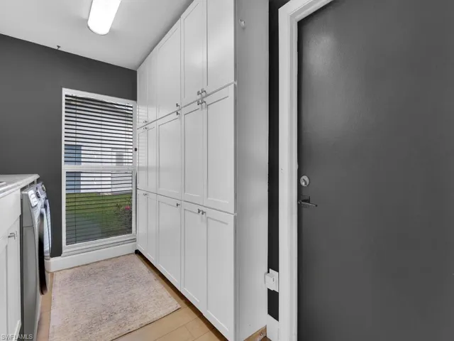 Clothes washing area featuring light hardwood / wood-style floors, cabinets, and washing machine and clothes dryer