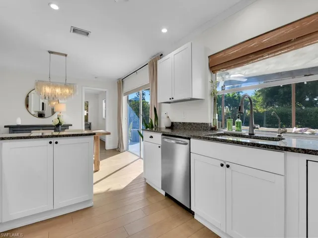 Kitchen featuring white cabinetry, dishwasher, sink, light hardwood / wood-style flooring, and pendant lighting