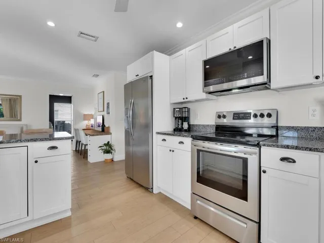 Kitchen with white cabinets, stainless steel appliances, crown molding, and light hardwood / wood-style floors
