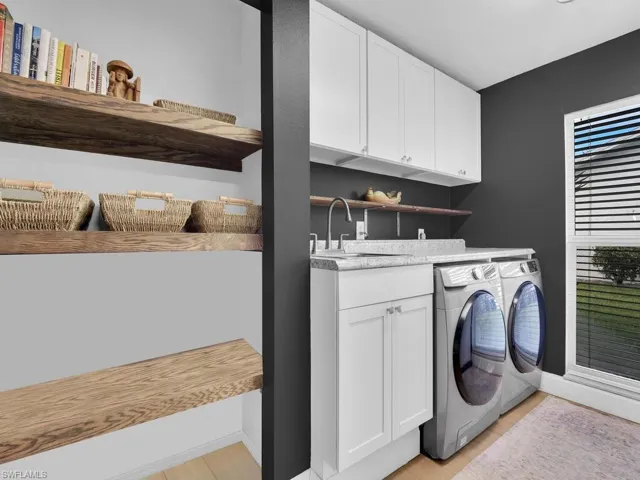 Washroom featuring separate washer and dryer, sink, cabinets, and light wood-type flooring