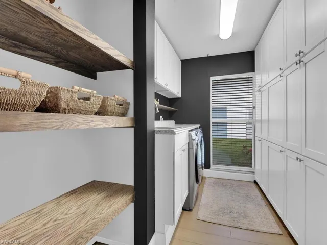 Clothes washing area featuring cabinets, washing machine and dryer, and light hardwood / wood-style flooring