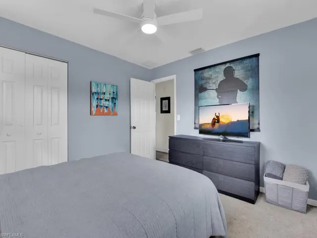 Carpeted bedroom featuring ceiling fan and a closet