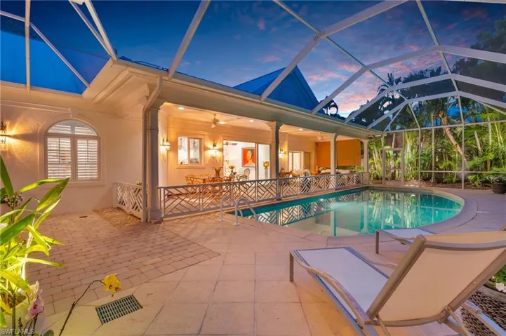 Pool at dusk featuring a lanai, ceiling fan, and a patio area
