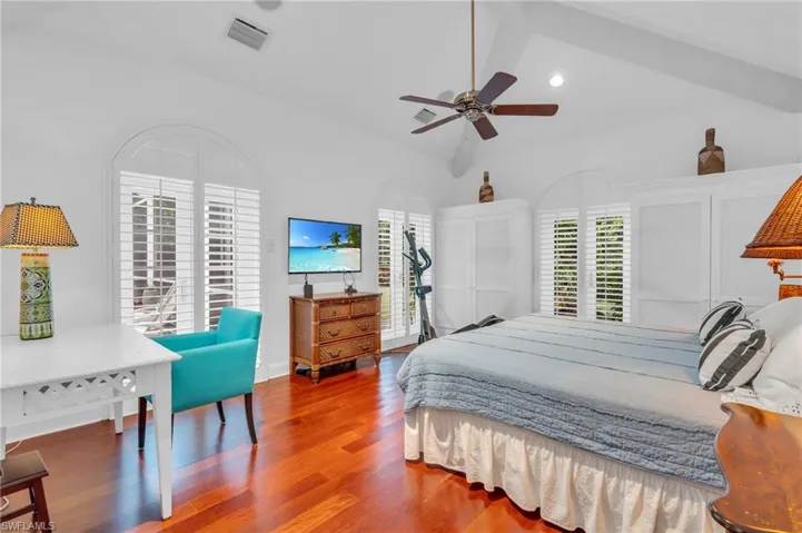 Bedroom featuring ceiling fan, lofted ceiling, hardwood / wood-style floors, and multiple windows