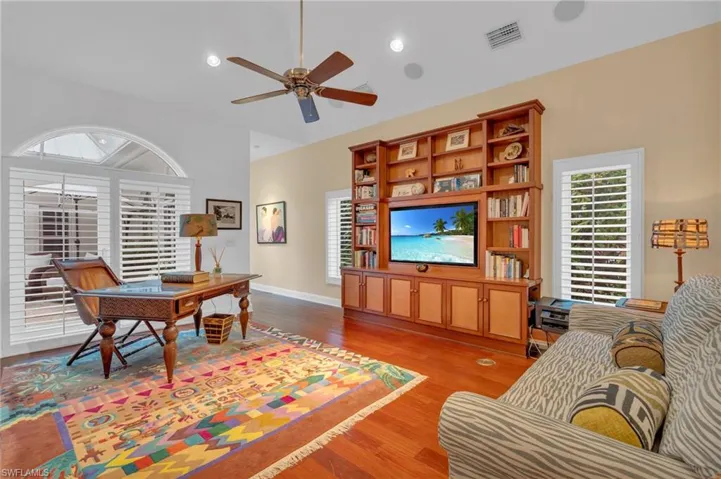 Living room with ceiling fan, vaulted ceiling, and light hardwood / wood-style floors