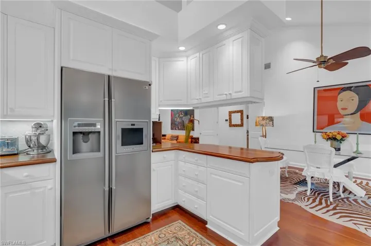 Kitchen with stainless steel refrigerator with ice dispenser, white cabinetry, tasteful backsplash, and light wood-type flooring