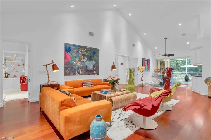 Living room with high vaulted ceiling, built in shelves, ceiling fan, and light wood-type flooring