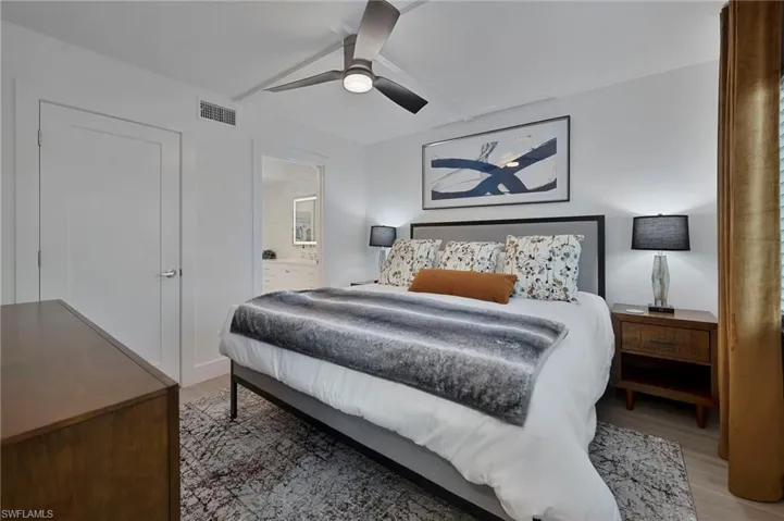 Bedroom with light wood-style floors, connected bathroom, and a ceiling fan