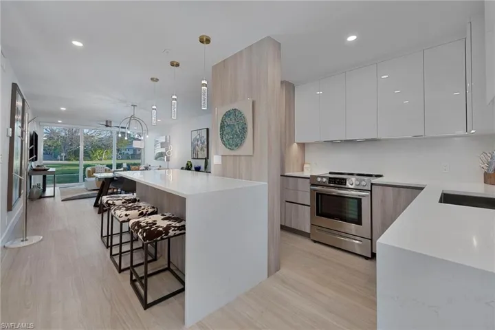 Kitchen with white cabinets, light stone counters, modern cabinets, stainless steel electric stove, and pendant lighting