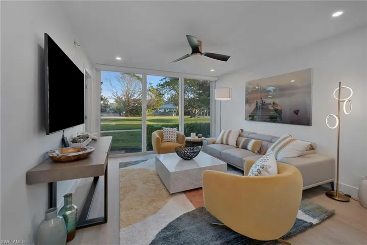 Living room featuring ceiling fan, a wall of windows, recessed lighting, and wood finished floors
