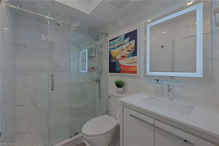 Full bath with vanity, a marble finish shower, and tile walls