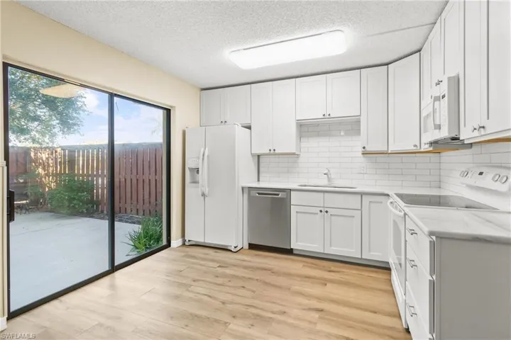 Kitchen featuring white cabinetry, sink, white appliances, and light hardwood / wood-style floors