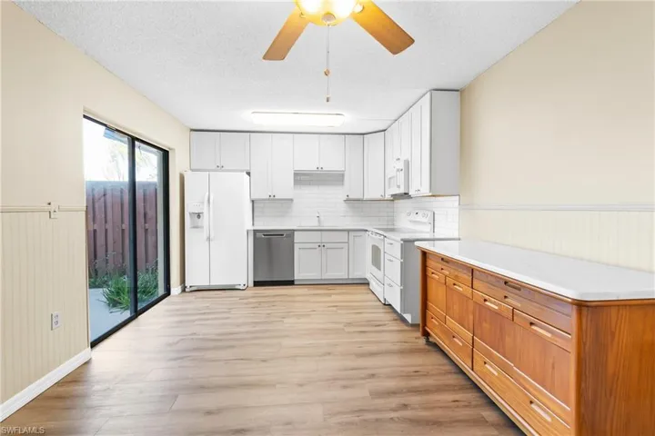 Kitchen featuring a textured ceiling, white cabinets, white appliances, and light hardwood / wood-style flooring