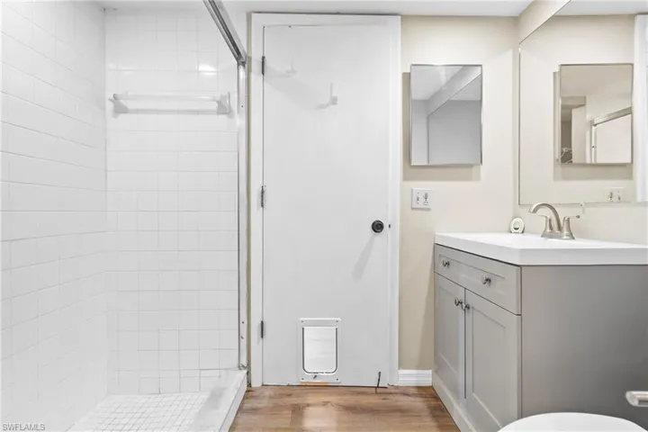 Bathroom featuring a tile shower, vanity, and hardwood / wood-style flooring