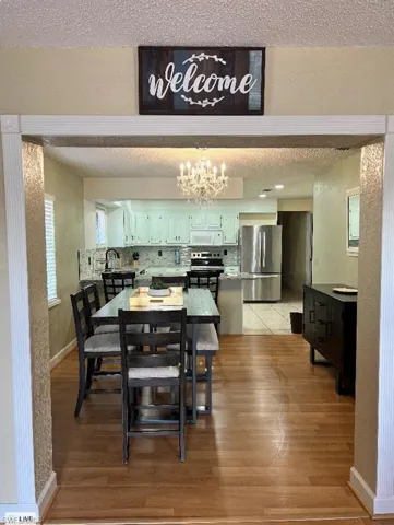 Dining space with a textured ceiling, light wood-style floors, baseboards, and a chandelier