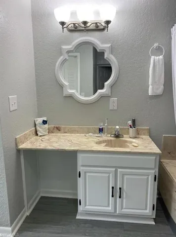 Bathroom featuring a textured wall, wood finished floors, and vanity