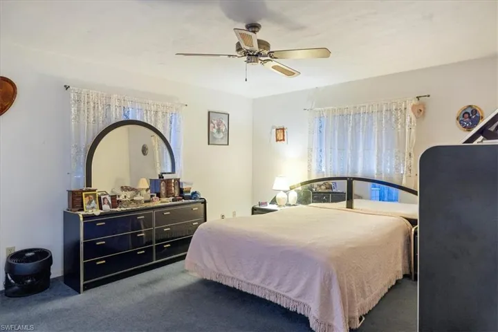 Bedroom featuring ceiling fan and dark carpet