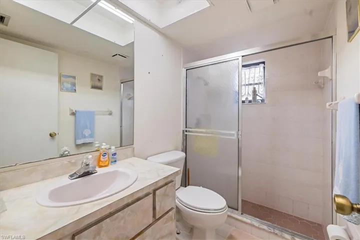Bathroom featuring toilet, a shower with shower door, and vanity