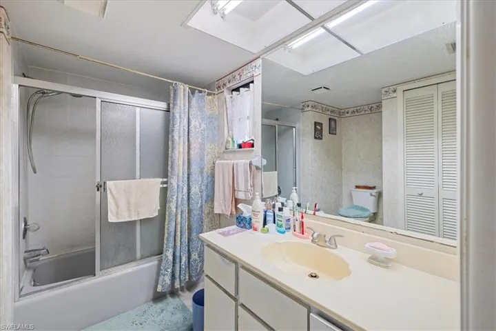 Full bathroom with toilet, shower / tub combo with curtain, and vanity