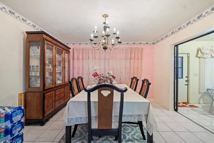 Dining area with light tile patterned floors and a chandelier