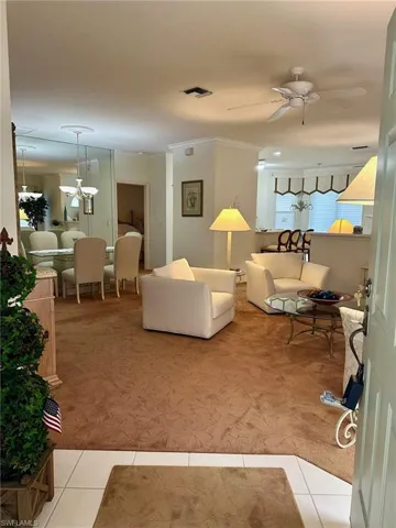 Carpeted living room featuring crown molding and ceiling fan