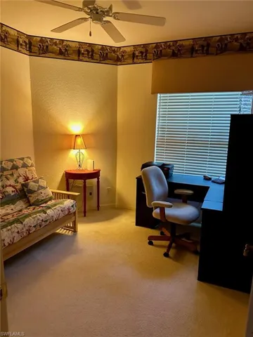 Carpeted home office featuring ceiling fan