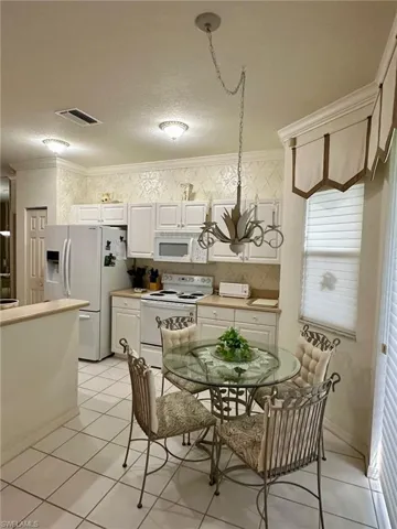 Tiled dining area featuring crown molding, a textured ceiling, and a chandelier