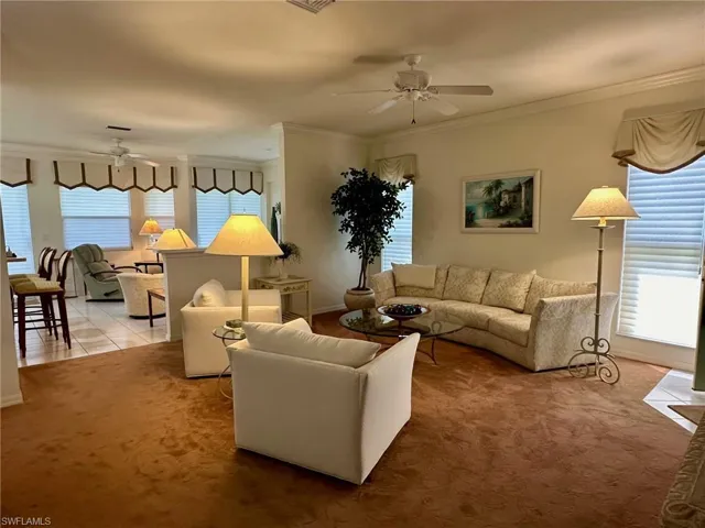 Carpeted living room with ceiling fan and ornamental molding