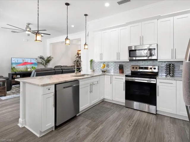 Kitchen with appliances with stainless steel finishes, a sink, open floor plan, a peninsula, and decorative backsplash