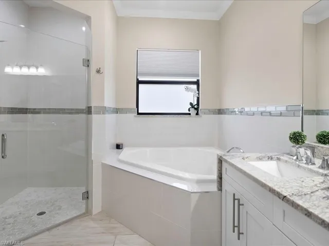 Bathroom featuring vanity, a garden tub, a shower stall, and ornamental molding