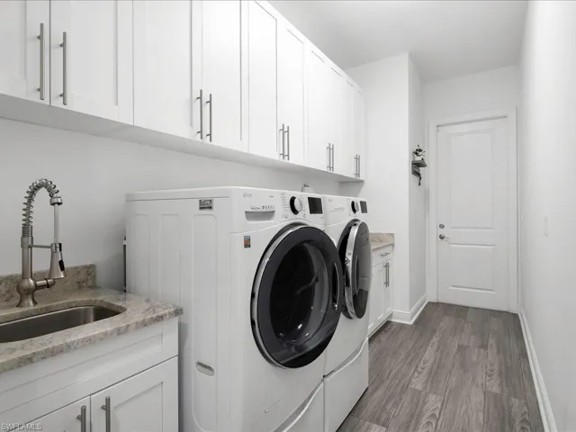 Washroom featuring washing machine and dryer, cabinet space, light wood-style floors, and baseboards