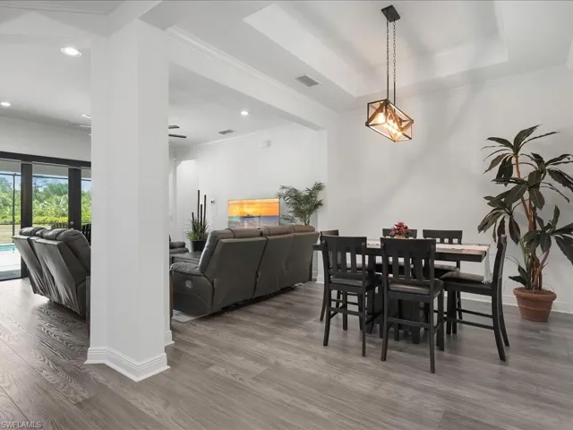 Dining space with wood finished floors, ornamental molding, baseboards, and recessed lighting