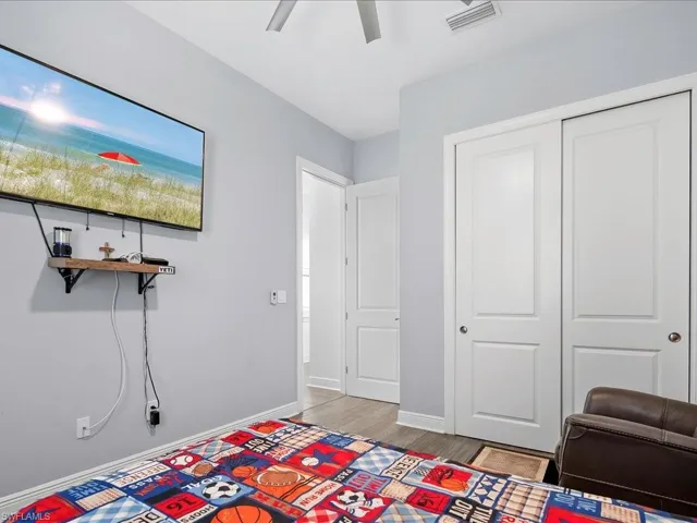 Bedroom with light wood finished floors, baseboards, a closet, and ceiling fan