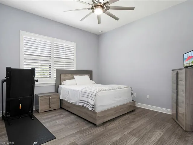 Bedroom featuring wood finished floors, baseboards, and a ceiling fan