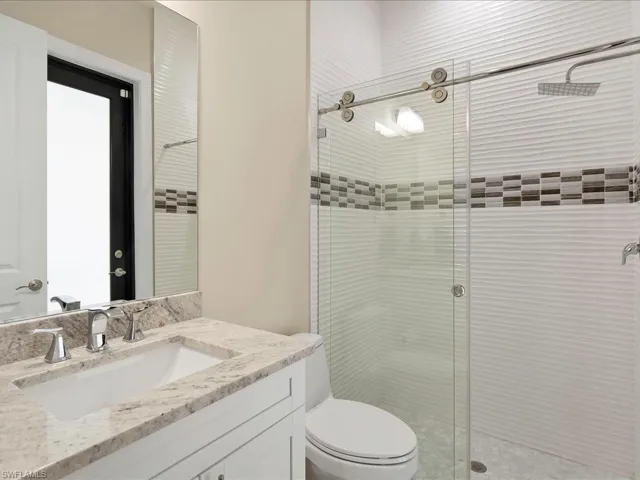 Full bath with a stall shower, toilet, and vanity