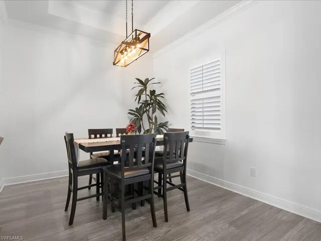 Dining room featuring wood finished floors, ornamental molding, a chandelier, and baseboards