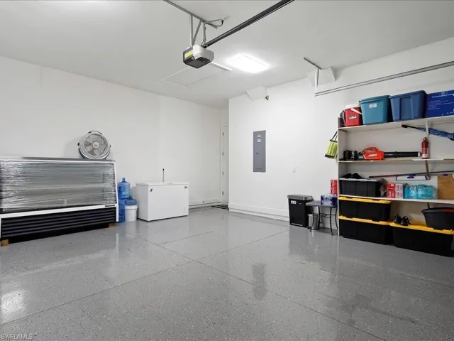 Garage with a garage door opener, electric panel, baseboards, and refrigerator