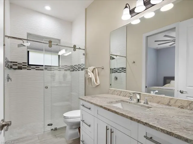 Ensuite bathroom featuring a stall shower, vanity, toilet, wood finished floors, and recessed lighting