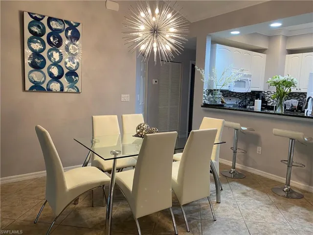 Tiled dining room featuring crown molding and a chandelier