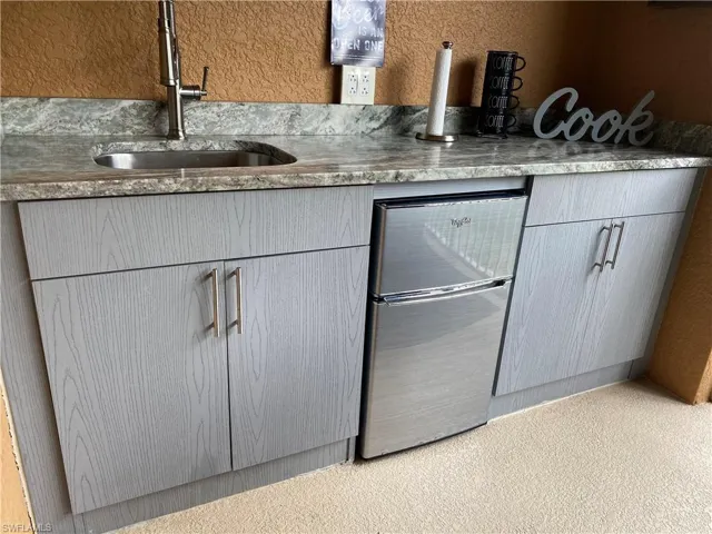 Outdoor Kitchen featuring stainless steel fridge, gray cabinets, and sink