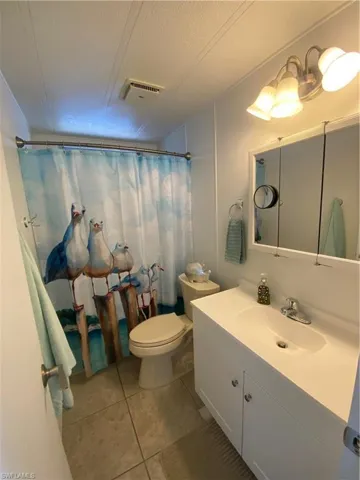 Bathroom with tile patterned flooring, vanity, a textured ceiling, and toilet