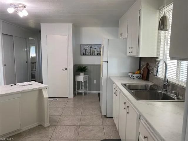 Kitchen with white cabinetry, sink, and light tile patterned floors