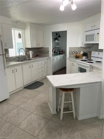 Kitchen featuring sink, range, fridge, a kitchen breakfast bar, and white cabinets