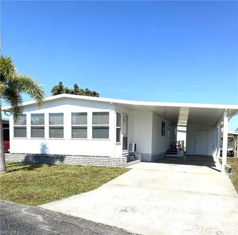 Manufactured / mobile home with a front lawn and a carport