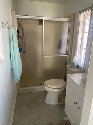 Bathroom featuring vanity, tile patterned floors, a shower with door, and toilet