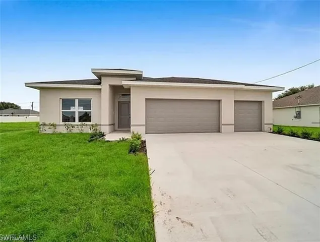 Prairie-style house with stucco siding, concrete driveway, a garage, and a front yard
