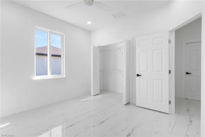 Unfurnished bedroom featuring light marble finish floors, a closet, ceiling fan, and recessed lighting