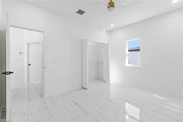 Unfurnished bedroom featuring recessed lighting, a closet, a ceiling fan, and light marble finish flooring