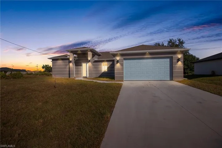 View of front of property with a front lawn, concrete driveway, a garage, and stucco siding